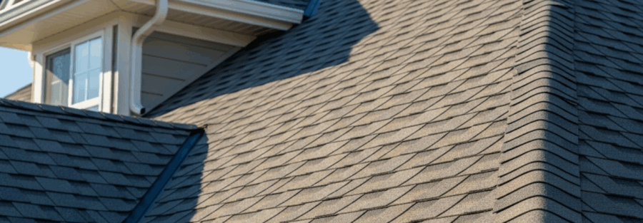 close-up image of a suburban home with an asphalt shingle roof by a trusted roofer near me