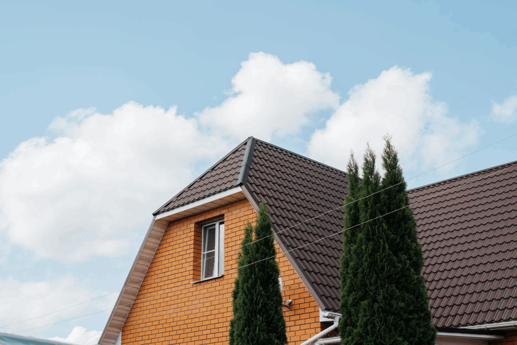 Building exterior, tiled metal brown roof of country house against blue sky outdoors