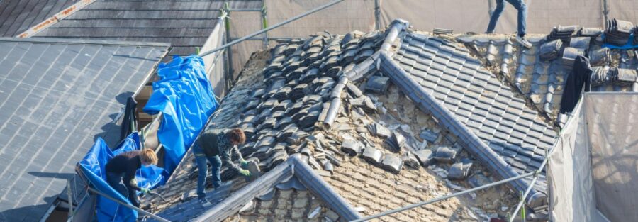 People working to tile a roof, representing job of a roof repair contractor