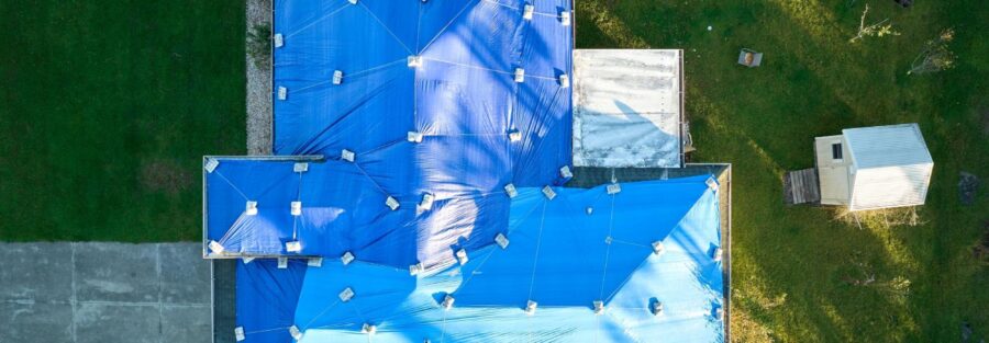 hurricane-damaged roof with tarp covering, symbolizing roof inspection for insurance