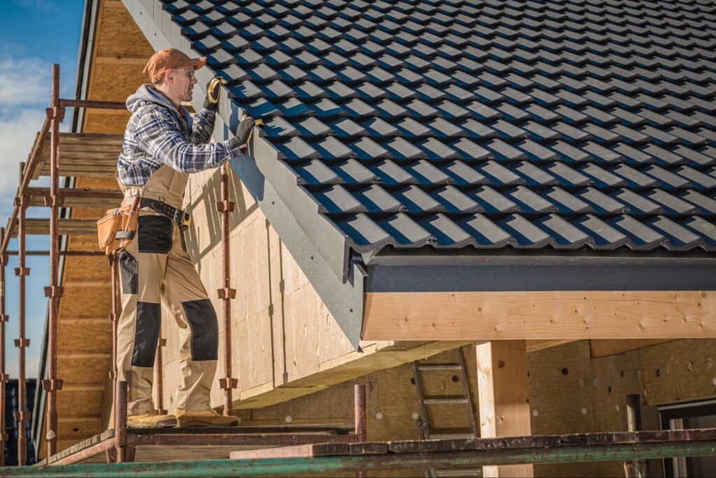 professional roofer installing ceramic roof tiles on a house roof