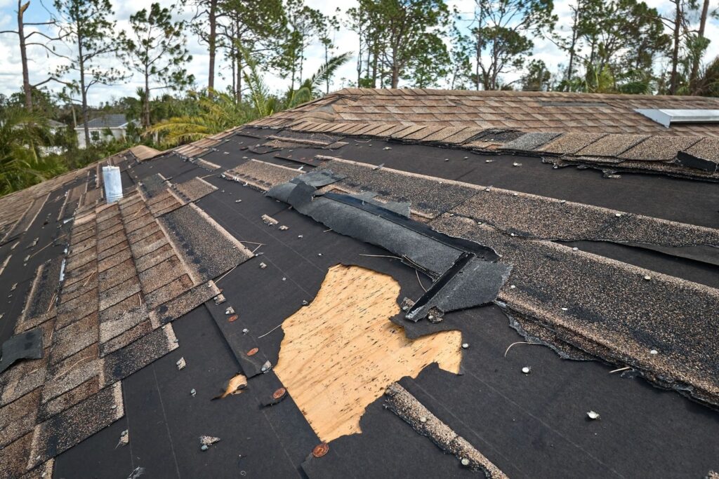 Damaged house roof with missing shingles after a hurricane