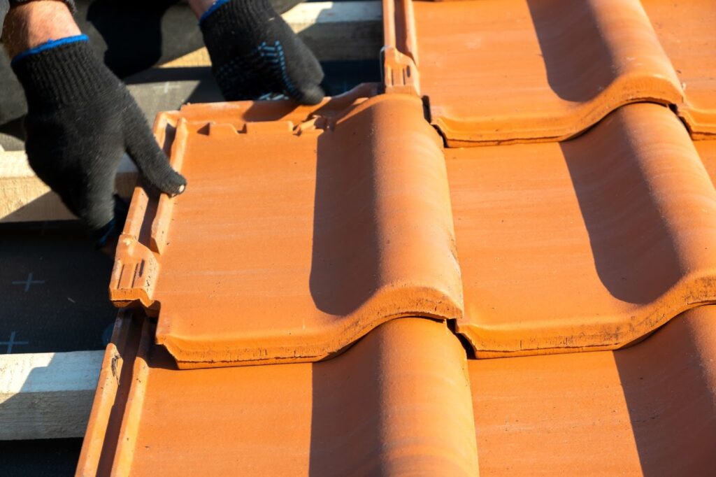 hands installing yellow ceramic roofing tiles