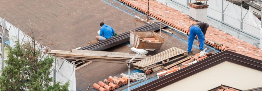 two men working on a roof, representing the need to tear off and replace roof in specific instances