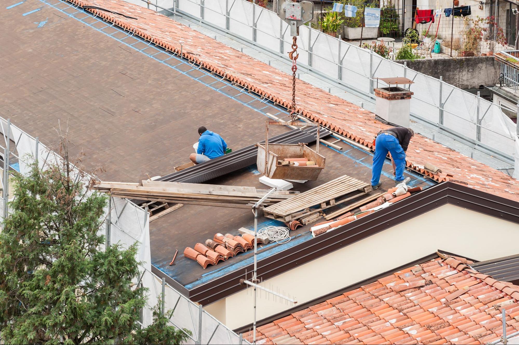 two men working on a roof, representing the need to tear off and replace roof in specific instances