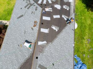 Workers installing new asphalt shingles during a residential roof replacement, prompting the question of new roof cost